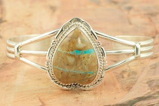 Genuine Boulder Turquoise set in heavy gauge Sterling Silver Bracelet. The cabochon is Boulder Turquoise, you can see the veins of Turquoise running through the host rock. The Boulder Turquoise Mine is located in northeast Nevada. It was discovered in 1970 by a Shoshone sheep herder. Production is small due to the remote location and winter weather. Boulder Turquoise is valued for both it's beauty and rarity. Every stone is unique. Created by Navajo Artist John Nelson. Signed by the artist.
